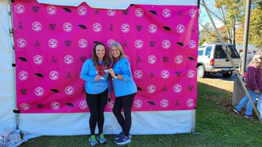 Joy and her best friend Vanessa holding their finisher medals after the Mount Desert Island Half Marathon