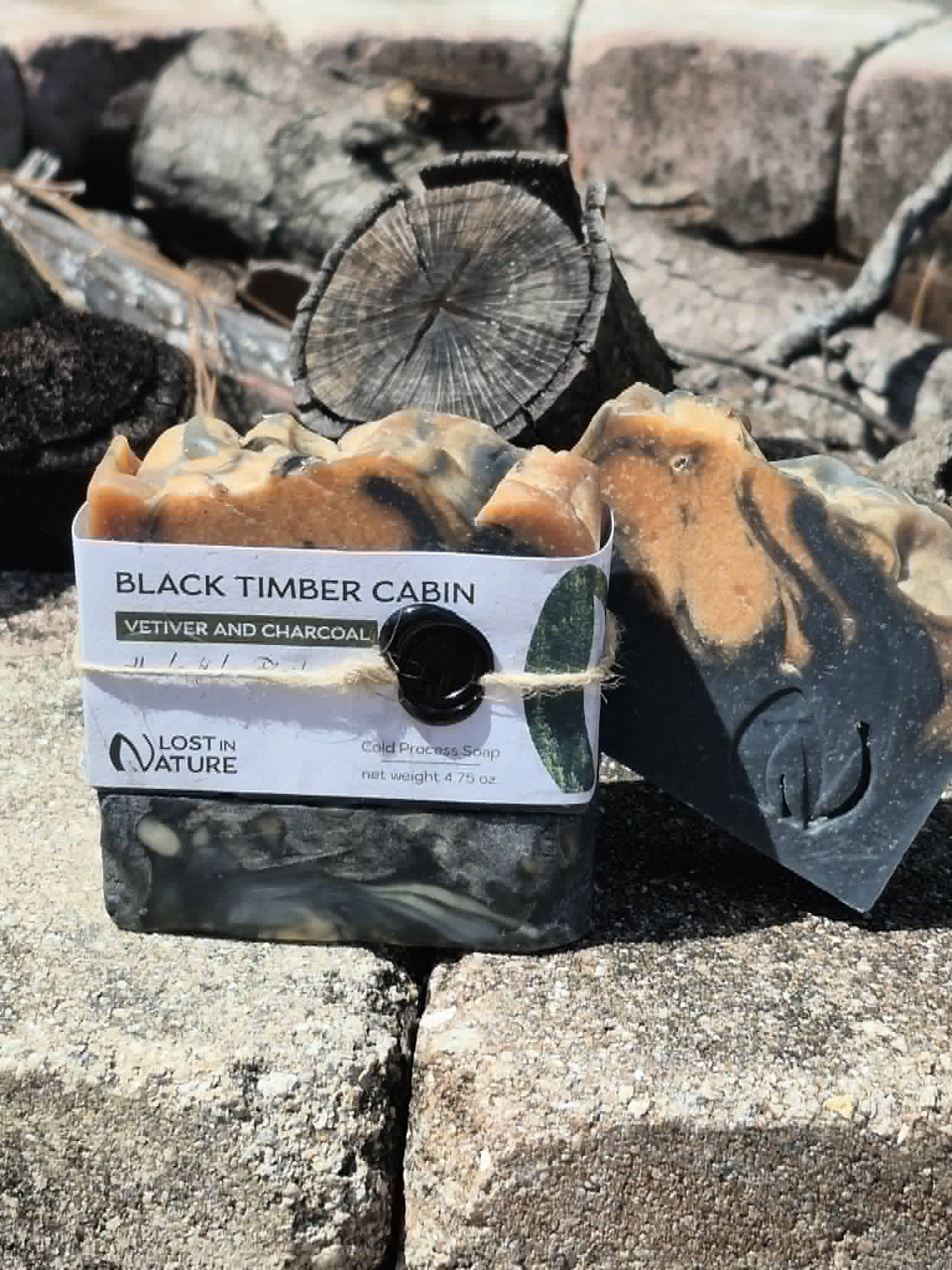 Black Timber Cabin charcoal soap photographed outdoors with split wood